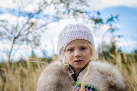 beautiful little girl in cap portrait in autumn meadowの写真素材