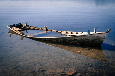 little wooden scuttled boat in the seaの写真素材