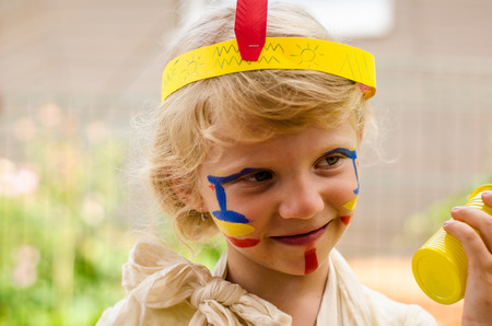 smiling little blond girl with Indian facepaintingの写真素材