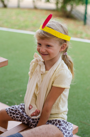 little blond girl with colorful headband and bandage on handの写真素材