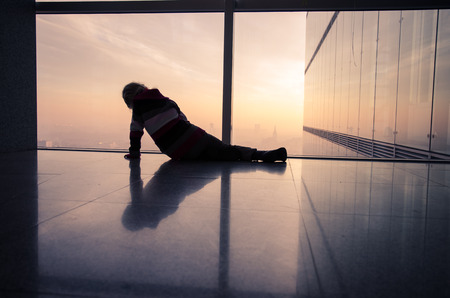 little child lying at the window to the cityの写真素材