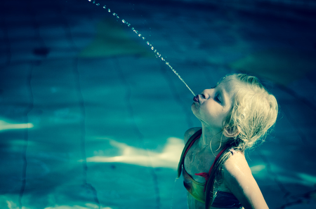 adorable kid spitting water in the swimming poolの写真素材