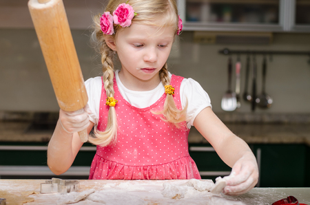 beautiful little girl in kitchen with rolling pinの写真素材