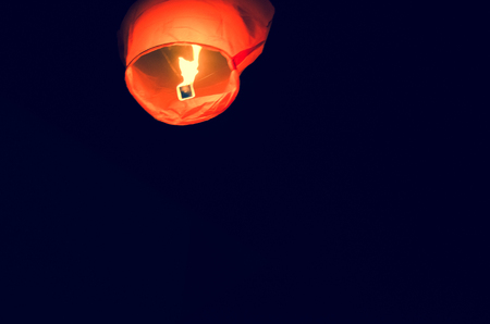 orange sky lantern of wish flying in the dark skyの写真素材