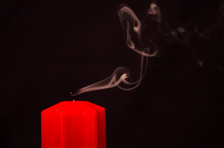 one orange candle blown out with black backgroundの写真素材