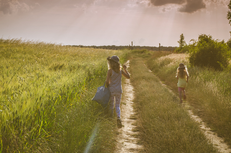girls walking in romantic colorful rural path among fieldsの写真素材