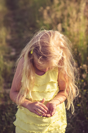 little blond girl walking in rural path among fieldsの写真素材