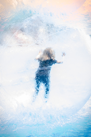 Little child inside the inflatable ball floating on waterの写真素材