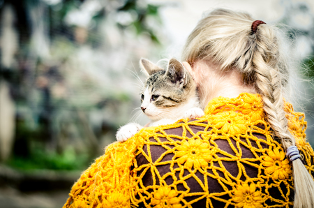 lovely little blond girl holding a cat back viewの写真素材