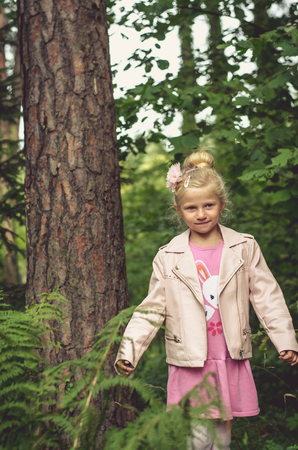 lovely blond little girl and green treesの写真素材