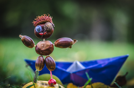 cute autumn pirate figure made of chestnut material posing with blue boatの写真素材