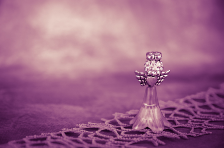 crystal angel decoration against purple backgroundの写真素材