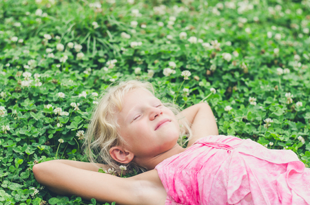 little lovely girl lying on the grass and enjoying lifeの写真素材