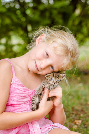 adorable cute kitty cat in hands of little child girlの写真素材