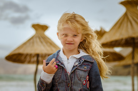 little blond girl with long hair portrait in windy weather at the seaの写真素材