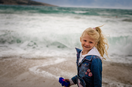 little girl portrait in windy weather at the seaの写真素材