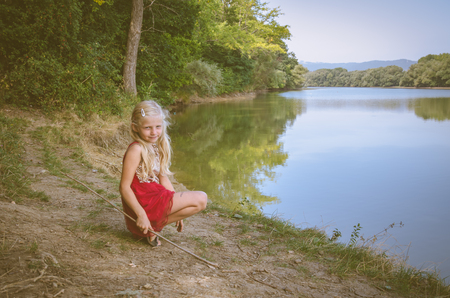 little kid squating by the pondの写真素材