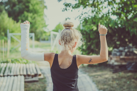 girl with broken hand in gypsum bandage back viewの写真素材
