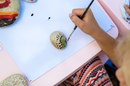 child painting pebbles with brushの写真素材