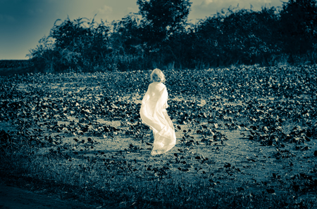 little scared child with mantle running in the fieldの写真素材