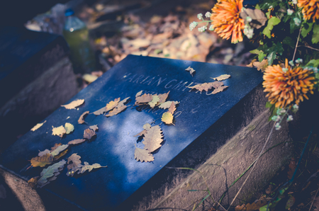 Graves with All Saint Day decoration and leaves in autumn atmosphereの写真素材