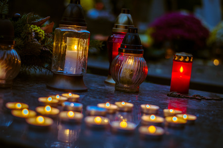 Colorful burning candles and chrysanthemum flower decoration  during All Saints Day at the cemeteryの写真素材