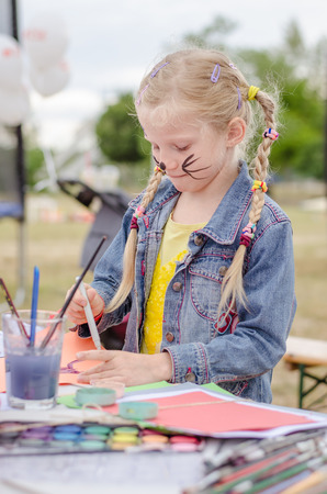adorable blond girl playing with play dough and creating figure on the tableの写真素材