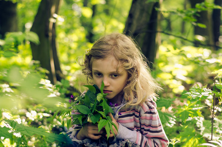 girl with long hair holding green leaves in spring forestの写真素材