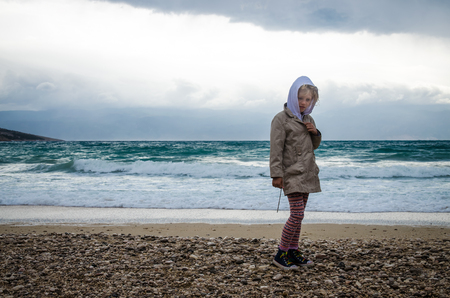 little child in rocky coastline in bad weatherの写真素材