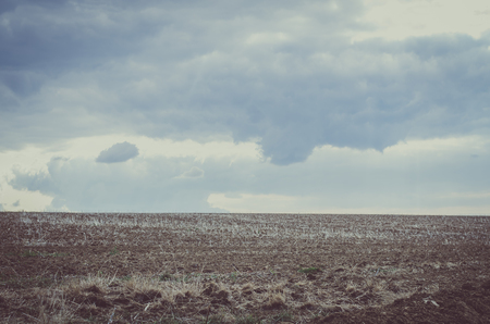 ploughed field and scary dark blue sky landscapeの写真素材