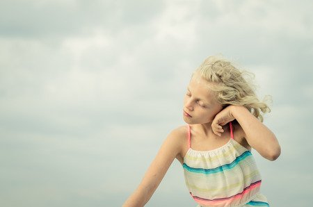 adorable little girl with blond hair portrait and blue skyの写真素材