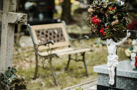 empty bench near the cross symbol in the cemetery during All Saints Dayの写真素材