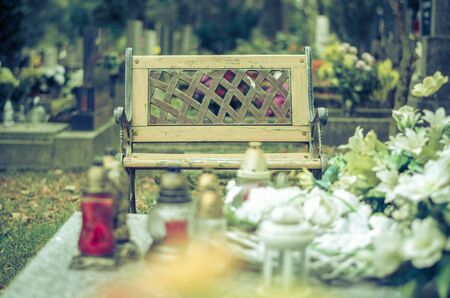 empty bench near the cross symbol in the cemetery during All Saints Day