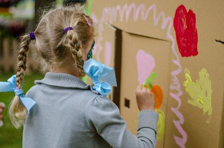 little cute child with face painting painting into big built paper house decorationの写真素材