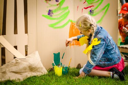 little cute child with face painting painting into big built paper house decorationの写真素材