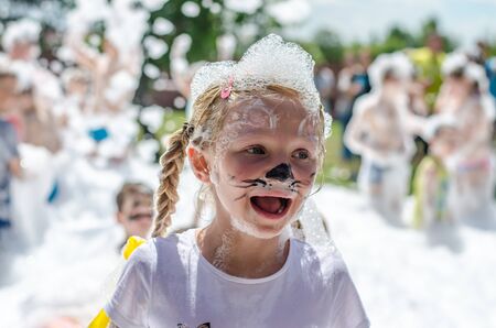 little lovely girl having fun in foam party in summer timeの写真素材
