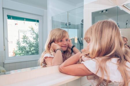 Adorable girl with long blond hair in the bathroomの写真素材