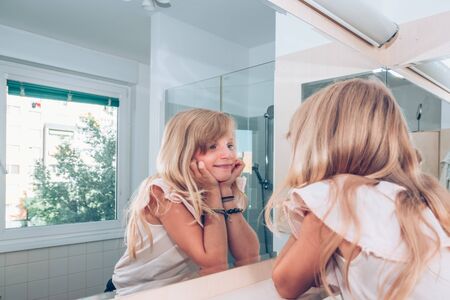 Adorable girl with long blond hair in the bathroomの写真素材