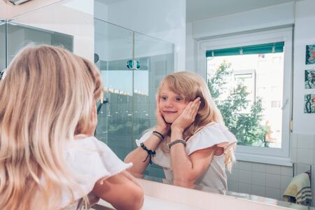 Close up portrait of adorable girl with long blond hair in the bathroomの写真素材