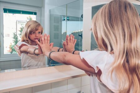 Close up portrait of adorable girl with long blond hair in the bathroomの写真素材