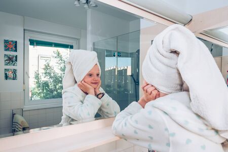 close up portrait of beautiful charming girl after shower looking into mirror in tidy bathroomの写真素材