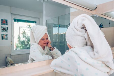 close up portrait of beautiful charming girl after shower looking into mirror in tidy bathroomの写真素材