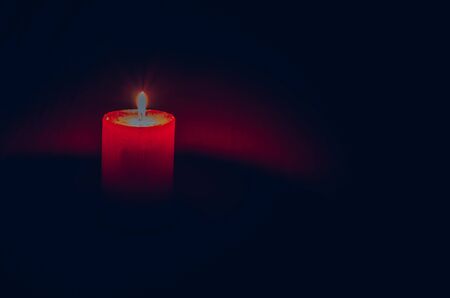 one red burning wax candle with black copy space backgroundの写真素材
