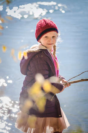 little child holding domestic cat and walking alone in sunny autumnal atmosphereの写真素材