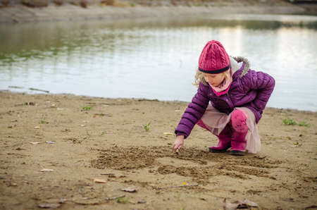little child holding domestic cat and walking alone in sunny autumnal atmosphereの写真素材