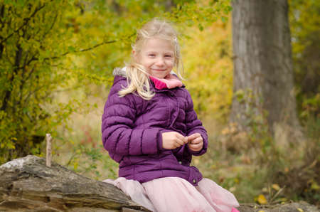 little child holding domestic cat and walking alone in sunny autumnal atmosphereの写真素材