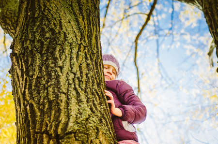 little child sitting in in the tree branch over the blue lake in scenic sunset time in colorful countrysideの写真素材