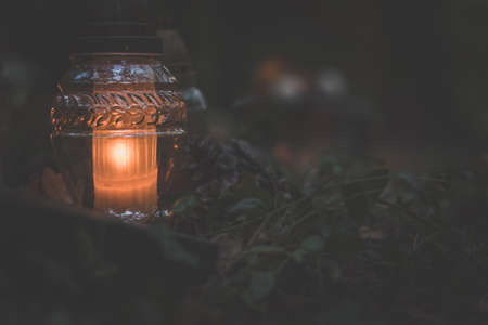 burning candles, colorful flowers and festive decorations on graves in graveyardの写真素材