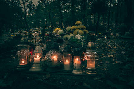 burning candles, colorful flowers and festive decorations on graves in graveyardの写真素材