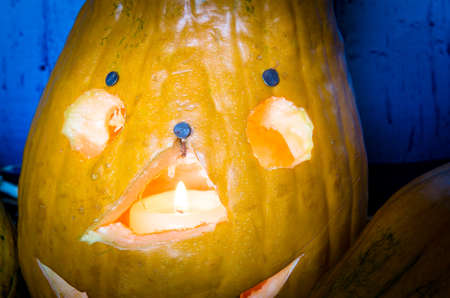 cute artificial halloween orange pumpkin decoration made from paper and glass with burning candle insideの写真素材